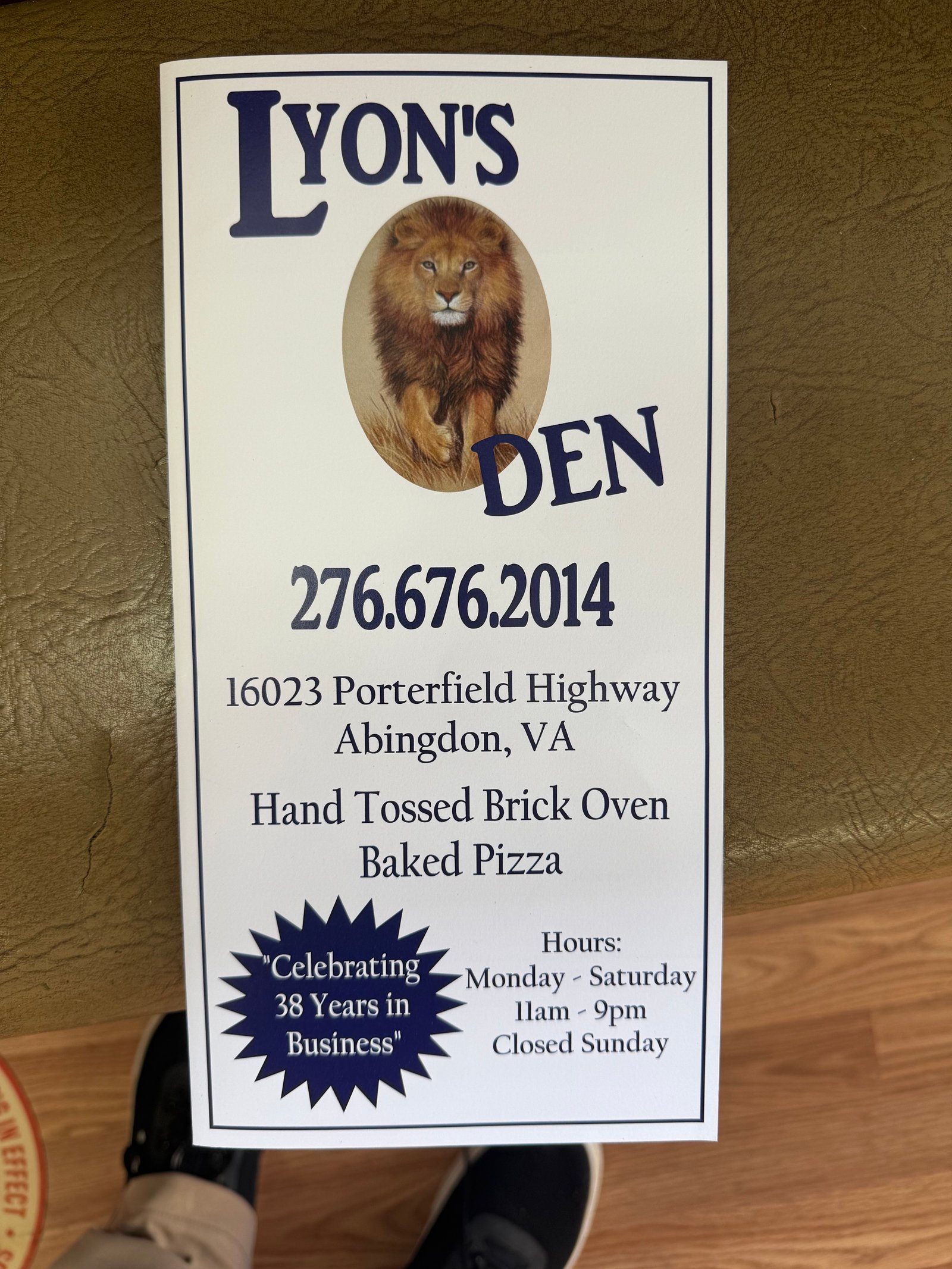 Lyon's Den counter card with lion logo, phone number, hours, and address